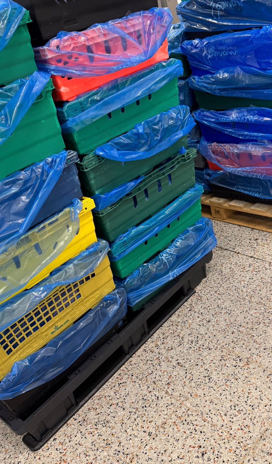 Stacks of colour-coded NEMB delivery crates on a pallet, loaded and ready for the day's rounds